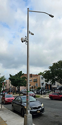 A streetlight pole with two camera attachments near the top of the pole.
